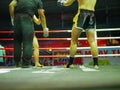 A referee giving a hand signal to begin / continue the fight between the Thai boxing fighters / boxers in the middle of the ring