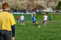 A referee standing in the foreground and Girls Playing Soccer on a soccer pitch Royalty Free Stock Photo
