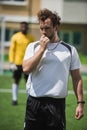 Referee whistling in whistle on soccer pitch during game Royalty Free Stock Photo