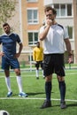 Referee whistling in whistle on soccer pitch during game Royalty Free Stock Photo