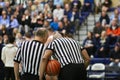 Referees in striped shirts consult during high school basketball game. Royalty Free Stock Photo