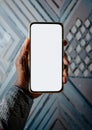 A hand holds a smartphone with a blank white screen against a textured, geometric background. Royalty Free Stock Photo