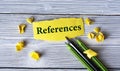 REFERENCES - word on a yellow tattered piece of paper with pencils and crumpled paper lumps on a light wooden background Royalty Free Stock Photo