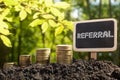 Referral - Financial opportunity concept. Golden coins in soil Chalkboard on blurred urban background