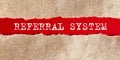 Referral System word written under torn paper, business concept