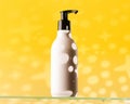 Refillable white dispenser bottle with a cosmetic product on a glass shelf on a yellow background with a shadow pattern.