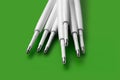 Refills for a ballpoint pen. Plastic refills for ballpoint pens. Pile of white ink refills on a green