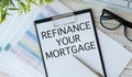 Refinance your mortgage - written on notepad on financial charts and graphs with pen Royalty Free Stock Photo