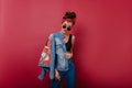 Refined caucasian girl in blue denim jacket posing in studio. Photo of slim sporty female model with black hair..