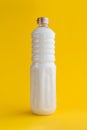Refined cured white coconut fat in a bottle on a yellow background