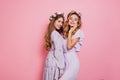 Refined girl with blonde wavy hair posing with sister on pink background. Pleased long-haired female model in flower Royalty Free Stock Photo