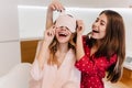 Refined girl in pink attire wears sleepmask in morning laughing in kitchen. Indoor photo of pretty brunette woman in red