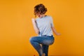 Refined short-haired lady wears dark-blue jeans jumping in studio. Attractive girl with wavy hairstyle dancing on yellow Royalty Free Stock Photo