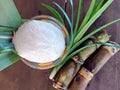 Refined sugar in a glass cup, with fresh sugar cane stems separate, on the old wooden floor Royalty Free Stock Photo