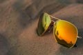 Reflecting sunglasses in the sand at the beach in summer. Sunset and people on beach reflecting in glasses