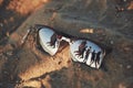 Reflecting sunglasses on a sandy beach in the summer, and the blue sky with people is reflected in glasses.