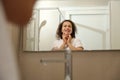 Reflection in mirror of pretty woman with radiant healthy skin, smiling looking at herself while doing spa procedures Royalty Free Stock Photo