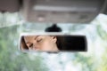 Reflection of a beautiful young woman relaxing with  closed eyes in the car rear view mirror. Royalty Free Stock Photo