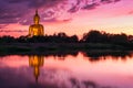 Reflection of big buddha statue in the river with purple sunset light and some clouds in the sky