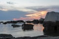 Reflection of the big stones and the sunset in the sea under the beautiful cloudy sky Royalty Free Stock Photo