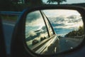 Reflection of blue sky with clouds in the mirror of a riding car in sunny day