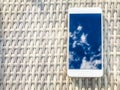 Reflection of blue sky with clouds in the phone-smartphone, which lies on a bright wicker table against the background. Blur and Royalty Free Stock Photo