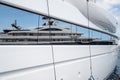 Reflection of a boat on a glossy surface of a huge yacht at sunny day, the chrome plated handrail, megayacht is moored