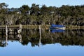 Reflection of a boat, the pier and the beautiful trees in a calm lake Royalty Free Stock Photo