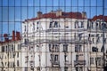 Reflection of building of classical architecture in mirror glass of skyscraper