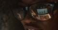 The reflection of the business graphics in the eyeglasses of the afro-american woman.