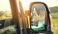 Reflection in a camper van rear-view mirror of a woman taking a picture with her cell phone