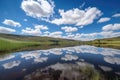 reflection of clear blue sky and fluffy white clouds in still lake Royalty Free Stock Photo