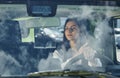 Reflection of clouds on the glass. Front view of woman that drives modern new car in the city Royalty Free Stock Photo