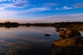 Reflection of clouds and twilight sky over the clear water surface surrounded by rocks Royalty Free Stock Photo