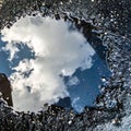Reflection of Cloudy Blue Sky in Dark Puddle on Gray Asphalt Road Surface Royalty Free Stock Photo