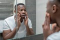 Dark-skinned young handsome man looking at himself in the mirror Royalty Free Stock Photo