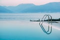 Reflection of the evening sky in the smooth water of the pool near the sea, against the backdrop of the mountains. Royalty Free Stock Photo