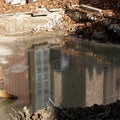Reflection in an excavation pit with groundwater on which a thick, greasy layer of heating oil floats Royalty Free Stock Photo
