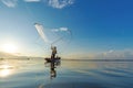 Reflection fisherman action when fishing net with dry alone tree on the boat in the lake outdoors sunshine morning blue sky backgr Royalty Free Stock Photo