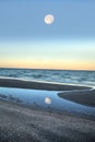 Reflection of the full moonset in a tidal pool in front of the ocean