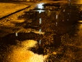 Reflection of glowing windows of house in puddle Royalty Free Stock Photo