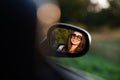 Reflection of a gorgeous young dark-haired girl in sunglasses in a side mirror of a car. Royalty Free Stock Photo