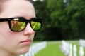 Reflection of graves and flags in a teenage girl`s sunglasses