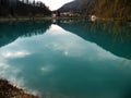 Reflection of hills,mountains, village and sky in turquise water