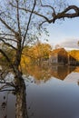 Reflection of the historic Yates Mill wooden building in the waters of a pond in autumn at dusk framed by colorful trees; vertical