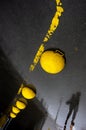 Yellow concrete hemispheres on wet asphalt.