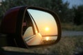 Reflection of landscape with beautiful sunset over calm river in car side view mirror, closeup Royalty Free Stock Photo