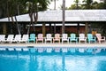 Reflection of lined chairs in the swimming pool of a hotel. Empty seating outdoors in a exotic resort with palm trees Royalty Free Stock Photo