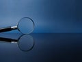 Reflection magnifying glass on a black acrylic board with blue background Royalty Free Stock Photo