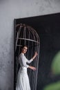 Reflection in the mirror of bride in cage on gray concrete background. Patriarchal marriage concept